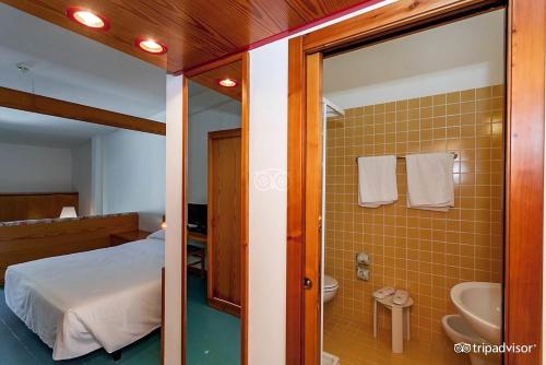 a bedroom with a bed and a bathroom with a sink at Multiproprietà presso hotel kyrie in San Domino