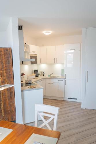 a kitchen with white cabinets and a table and chairs at Inselblume 43 - Zentrumsnahe, moderne Ferienwohnung in Burg in Burg auf Fehmarn