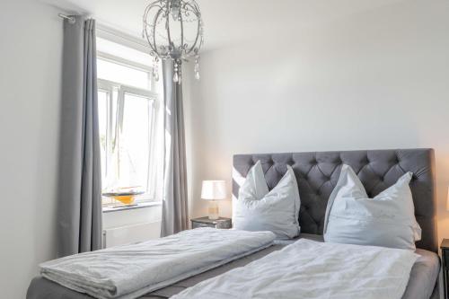 Un dormitorio con una cama con sábanas y almohadas blancas. en Inselblume 47 - Luxus Ferienwohnung in Burg, mit Dachterrasse, en Burg auf Fehmarn