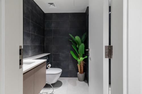 a bathroom with a toilet and a plant at Sahab - Hermes Leather Home in Sharjah