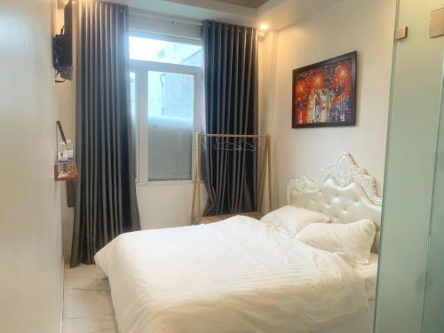 a bedroom with a white bed and a window at Hailey's House in Da Lat