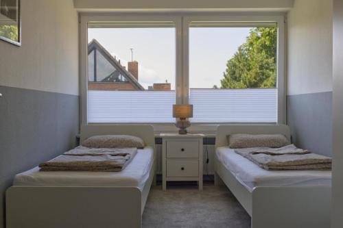 due letti in una stanza con due finestre di Inselblume 58 - Ferienwohnung mit Balkon in Neue Tiefe a Neue Tiefe Fehmarn