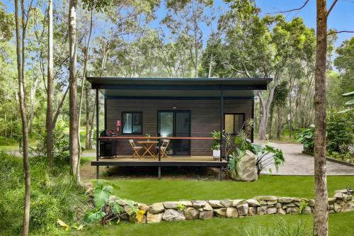 a tiny house in the woods with a deck at Cabin By The Creek Hidden Oasis 