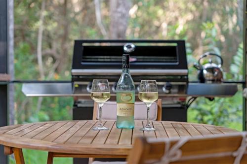 a bottle of wine and two glasses on a table at Cabin By The Creek Hidden Oasis 
