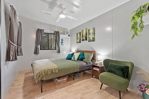 a bedroom with a bed and a green chair at Cabin By The Creek Hidden Oasis 