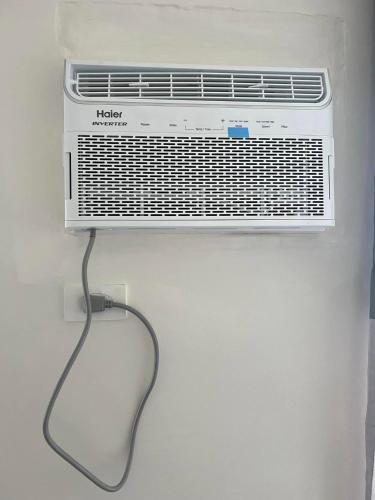 a white air conditioner hanging on a wall at Brittany Bliss Staycations at SMDC HOPE RESIDENCES in Trece Martires