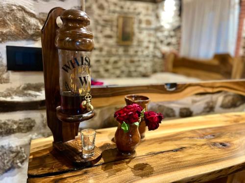 a wooden table with a bottle and two glasses and flowers at Vechia Villa Mitllari in Tushemisht