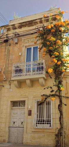 a building with a balcony and a tree at The Anchor Townhouse in St Paul's Bay
