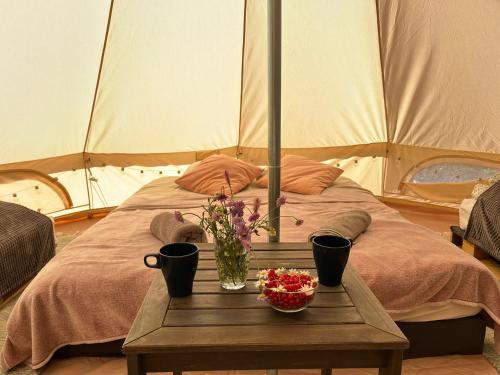 a table with flowers on a bed in a tent at Mazury Glamping Kruklanki Polana Życzeń in Kruklanki