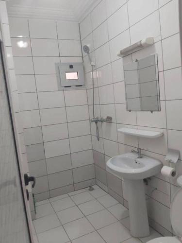 a white bathroom with a sink and a mirror at Hotel Carmel Cocody in Abidjan
