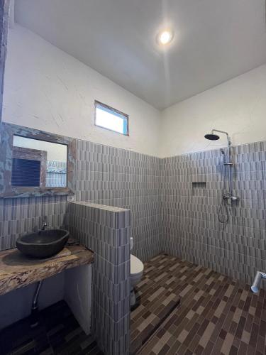 a bathroom with a sink and a toilet at Dolot Guest House Amed Beach in Amed