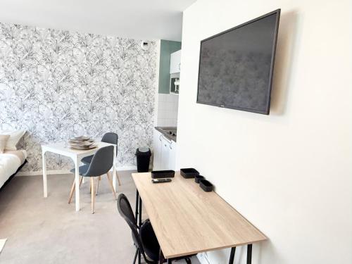 a living room with a table and a tv on a wall at Studio clair rivage centre-ville in Lorient