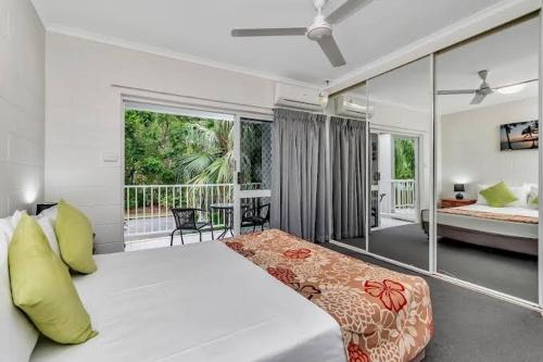 a bedroom with a large bed and a balcony at Barrier Townhouse in Port Douglas