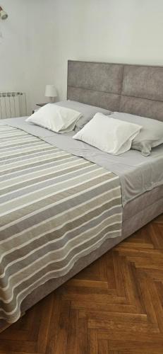 a large bed with white pillows on a wooden floor at Cozy house Luana in Lopud Island