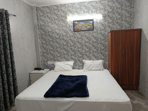 a bedroom with a large white bed and a cabinet at Family Hotel -1 Min Walk in Nizamuddin Railway Station in New Delhi