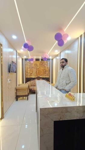 a man sitting at a kitchen counter with purple balloons at Family Hotel -1 Min Walk in Nizamuddin Railway Station in New Delhi