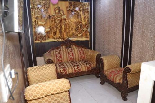 a room with two chairs and a couch and a painting at Family Hotel -1 Min Walk in Nizamuddin Railway Station in New Delhi