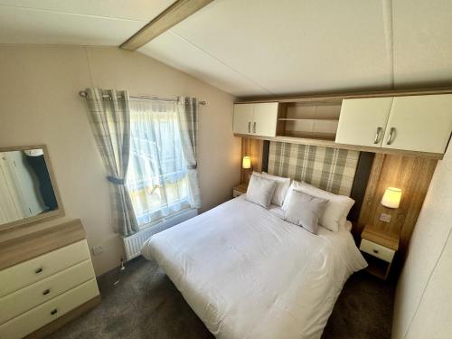 a small bedroom with a white bed and a window at North Bay Leisure Park in Bridlington
