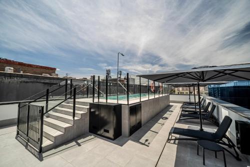a rooftop patio with a swimming pool and umbrellas at ITC Madrid by Soho Boutique in Madrid