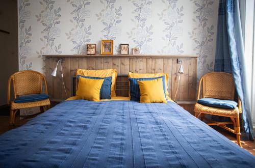 a bedroom with a blue bed with two chairs at Ambiance Morvan in Ouroux en Morvan