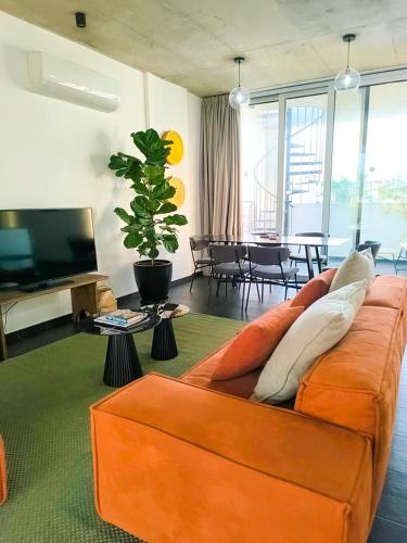 a living room with an orange couch and a television at Bridge House 301-3BR Penthouse in Limassol