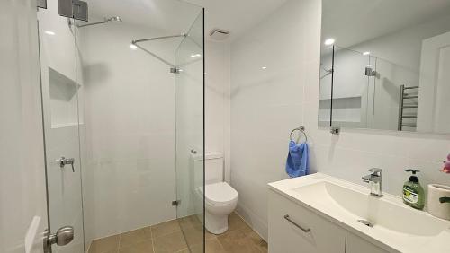 Un baño con ducha, inodoro y lavabo. en Direct Beachfront Sunrise Apartment - The Coachhouse, en Narrabeen