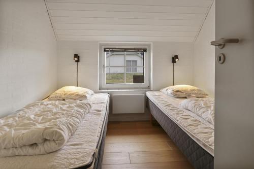 two beds sitting in a room with a window at Thatched house with spa and pool by the sea - SJ67 in Harboør