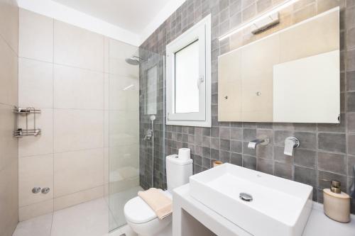 a bathroom with a sink and a toilet and a mirror at Villa Kira in Trapezaki