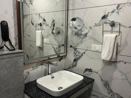 a white bathroom with a sink and a mirror at SABU's GRAND ROYALE HOTEL in Trivandrum
