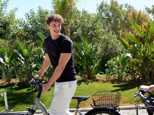 a young man is smiling while holding a bike at Grecotel LUXME Kos in Kos Town