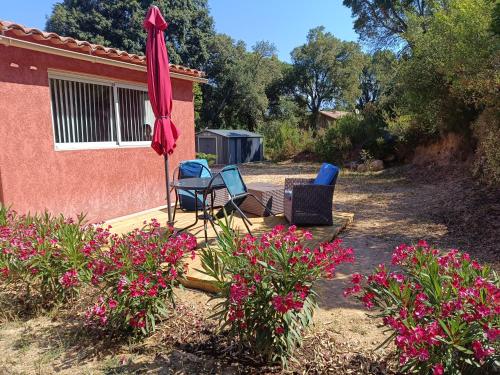 a patio with two chairs and an umbrella and flowers at chambre d'hôte cosy L'AGHJA in Carbuccia