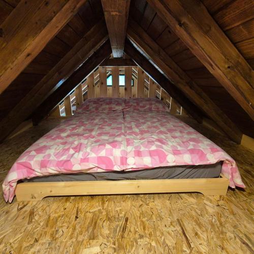 a large bed in a wooden attic room at Glamping Fikfak in Bled