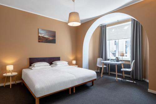 a bedroom with a bed and a window and a table at RIJA Riga City Centre Hotel in Rīga