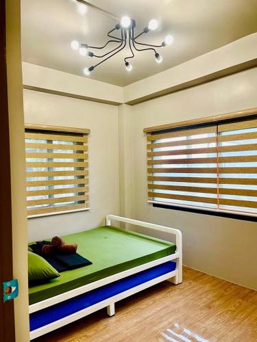 a bedroom with a bed in a room with windows at Newlives Transient 2 Hillside - 1st Floor in Baguio