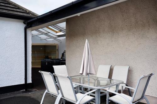 a glass table with white chairs and an umbrella at Ogham View in Mountfield