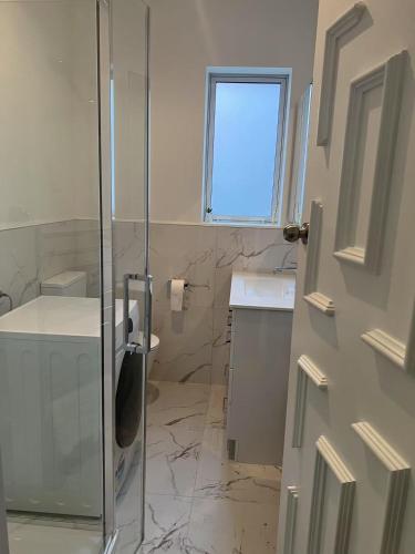 a bathroom with a glass shower stall and a sink at Sun-kissed house in Auckland