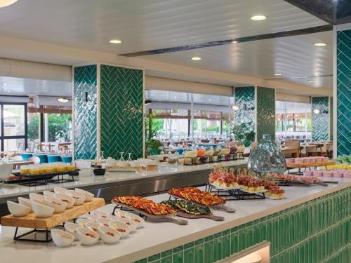 a buffet line with food on display in a restaurant at H10 Cambrils Playa in Cambrils