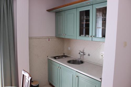 eine Küche mit grünen Schränken und einem Waschbecken in der Unterkunft Villa Velzon Guesthouse in Budva