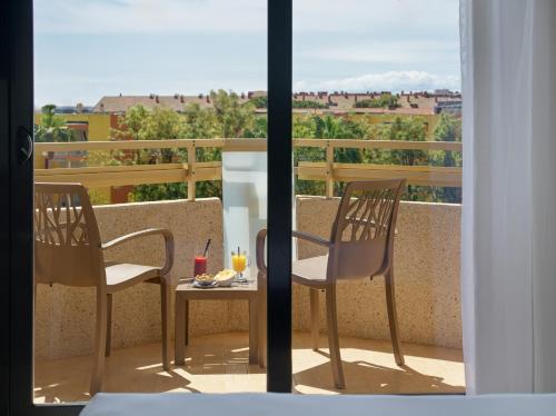 a balcony with two chairs and a table with drinks on it at H10 Cambrils Playa in Cambrils