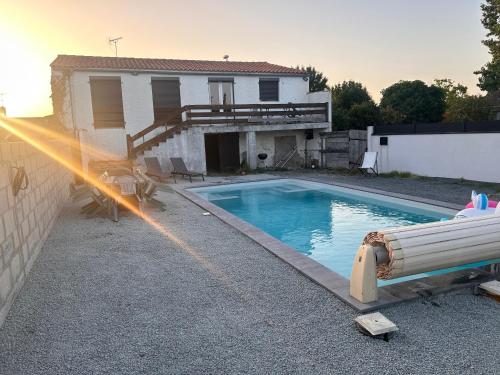 une piscine avec un tuyau d'arrosage devant une maison dans l'établissement Maison à Oléron avec piscine chauffée et privée, à Dolus-d'Oléron