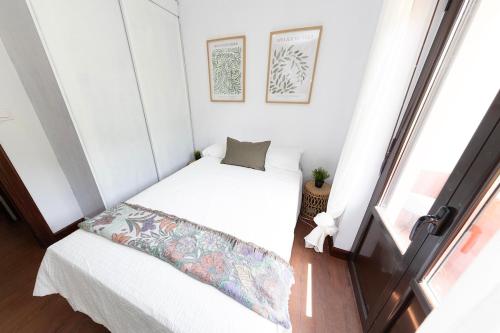 a small bed in a small room with a window at Apartamento El Cachupín in Laredo