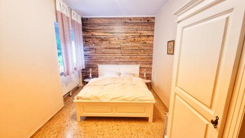 a bedroom with a bed and a wooden wall at Lovely Alps ski apartment on Alpe Adria bike trail in Pontebba