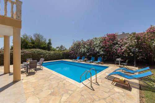 a swimming pool with chairs and a table next to a house at Villa Tsikkos Dio in Limassol