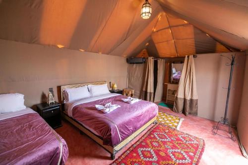 a bedroom with two beds in a tent at lina safari luxury camp in Merzouga