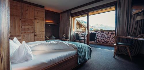 a hotel room with a bed and a large window at Jungbrunn Der Gutzeitort in Tannheim