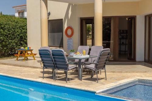 a table and chairs next to a swimming pool at Villa Tsikkos Dio in Limassol