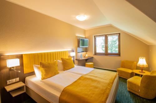 a hotel room with a bed and a chair at Ferien Hotel Cottbus in Kolkwitz