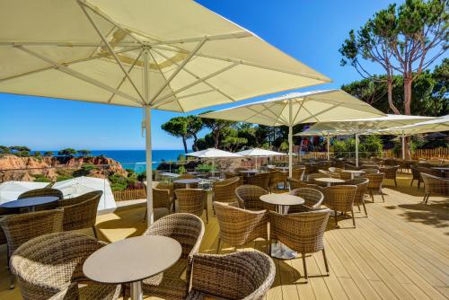 an outdoor restaurant with tables and chairs and umbrellas at 3HB Falesia Beach in Albufeira