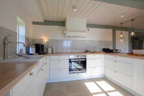 a kitchen with white cabinets and a sink and an oven at Tammwarftshof in Pellworm