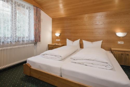 a bedroom with a bed with white pillows and a window at Haus Rosemarie in Serfaus